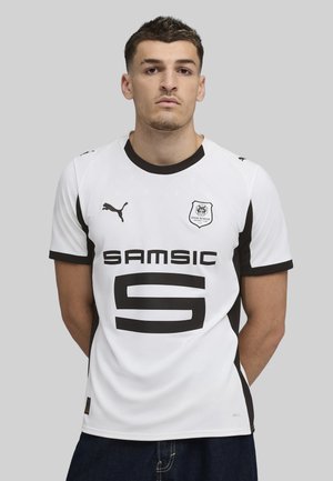 Hvid kortærmet fodboldtrøje med sorte accenter. Har stort sort "SAMSIC" logo, nummer "5" og broderet emblem på venstre bryst.