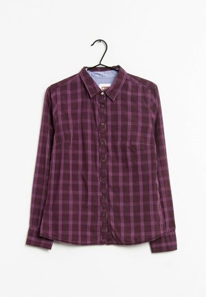 Camisa de manga larga a cuadros en morado y ciruela oscura con botones, colgada en una percha negra sobre un fondo blanco.