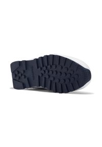 Suela de zapatilla deportiva blanca con profundas ranuras y una suela de goma azul con protuberancias redondeadas para mayor tracción. Logotipo "Reebok" grabado en el talón.
