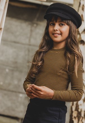 Lange mouw bruine gestreepte top gecombineerd met donkere broek en een zwarte baret. Gladde textuur, casual ontwerp en speelse uitstraling.