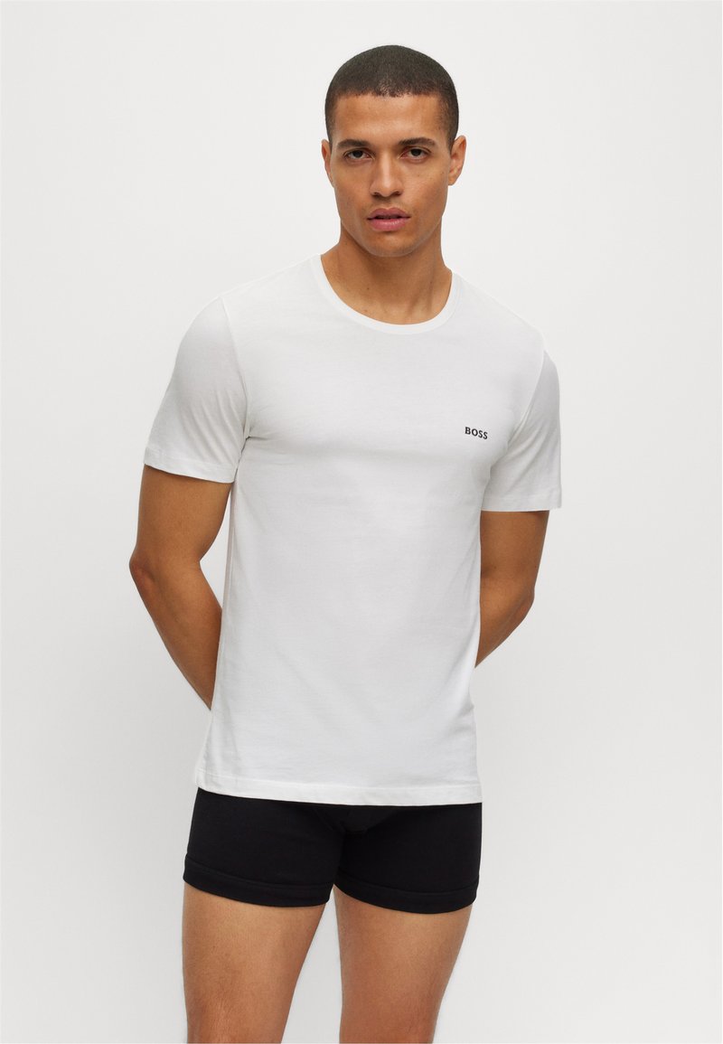 Hvit bomulls t-skjorte med rund hals og korte ermer, med en liten svart "BOSS" logo på venstre bryst. Sorte shorts.