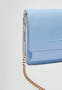 Borsa a tracolla in pelle testurizzata di colore blu chiaro con una catena dorata e logo impresso. Presenta una chiusura a pattina e bordi lisci.