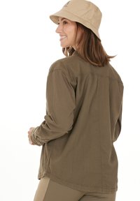 Khaki skjorta med knappar och långt ärm samt en avslappnad passform. Har subtila sömmar, sidofrackar och en mjuk textur.