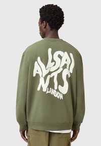 Felpa verde oliva con testo grafico bianco sul retro, polsini e orlo a coste, vestibilità rilassata, materiale in cotone morbido e scollatura a girocollo.