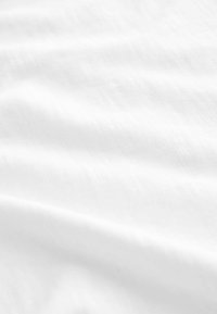 Tessuto bianco con una superficie morbida e strutturata, che mostra sottili variazioni di tonalità e un aspetto leggero e fluido.