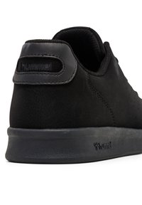 Czarny sneaker z gładką górą z zamszu, wyściełanym kołnierzem i gumową podeszwą. Posiada perforowane detale oraz wytłoczone logo na pięcie.