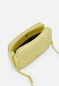 Borsa a tracolla trapuntata gialla in ecopelle. Presenta una chiusura a doppia cerniera e una tracolla a catena per maggiore versatilità. Interno foderato in tessuto scuro.