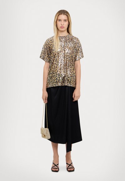 Top con stampa leopardata in paillettes oro e marrone, a maniche corte. Abbinato a una gonna nera, ampia, e sandali neri con lacci. Borsa a tracolla dorata.