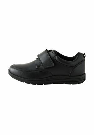 Chaussure en cuir noir avec un bout arrondi, fermeture à bande Velcro, détails texturés sur le dessus et semelle extérieure en caoutchouc durable.