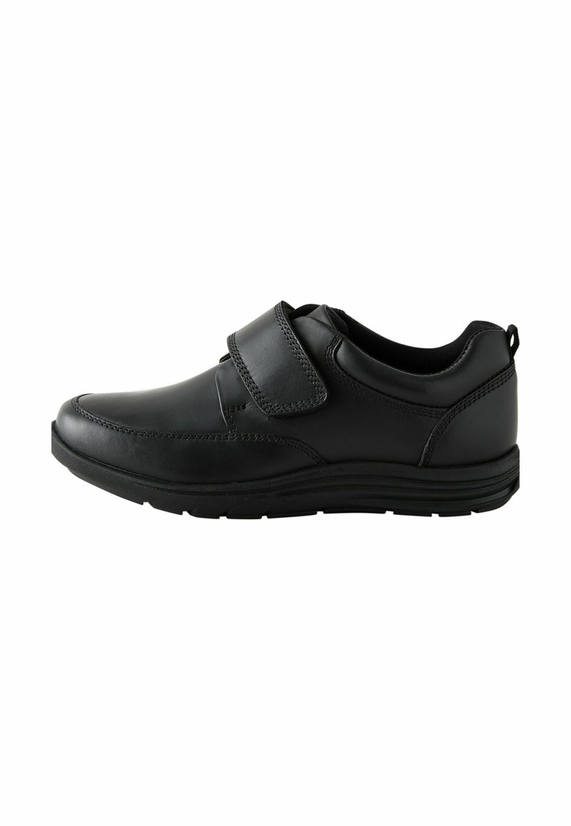 Chaussure en cuir noir avec un bout arrondi, fermeture à bande Velcro, détails texturés sur le dessus et semelle extérieure en caoutchouc durable.