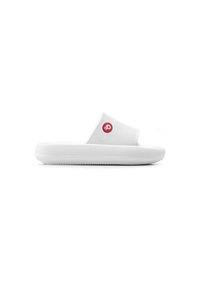 Sandalias blancas de tipo slip-on con un empeine texturizado y una suela plana y gruesa. Presentan un logo circular rojo en el lateral. Diseño simple y minimalista.