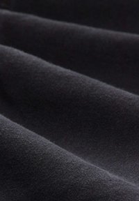 Czarna, teksturowana tkanina z miękkimi, gładkimi falami. Materiał wydaje się gruby i lekko puszysty, prezentując jednolity, ciemny odcień.