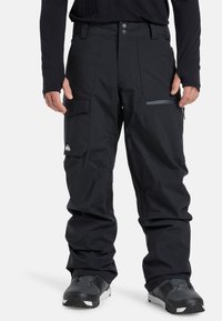 Zwarte sneeuwbroek van waterbestendig materiaal, met een ritszak, een verstelbare tailleband en gebogen knieën voor een gemakkelijke beweging.