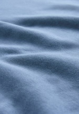 Mekana plava tkanina s blagim nabora i glatkom, pletenom teksturom vidljivom u izbliza.