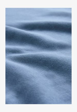 Soft blue fabric with gentle folds and a smooth, knit texture visible in close-up.