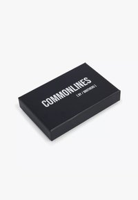 Melns taisnstūrveida lodziņš ar baltu tekstu "COMMONLINES [ BY / BROTHERS ]" augšpusē uz balta fona.