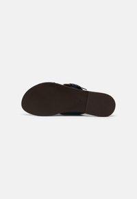 Semelle plate marron avec une prise texturée. Dispose d'une boucle ajustable sur une sangle bleue. Design simple et fonctionnel avec une finition lisse.