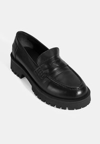 Zwarte lederen loafer met een ronde neus, verhoogde naaddetails en een dikke zwarte rubberen zool met een profielpatroon voor grip.