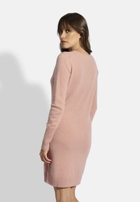 Světle růžové pletené šaty s fitted střihem, dlouhými rukávy a žebrovanými manžetami a lemem, s kulatým výstřihem a jemnou strukturou.