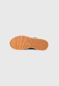 Black athletic shoe sole with a textured orange rubber outsole, featuring a geometric tread pattern for improved grip and traction.