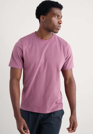 Kortærmet t-shirt med rund hals i dæmpet mauve bomuldsstof. Glat overflade med en afslappet pasform, parret med mørke bukser.