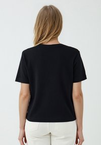 Zwarte katoenen t-shirt met korte mouwen, een ronde hals en een relaxte pasvorm, met eenvoudige stiksels en zonder zichtbare logo's.