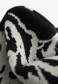 Primo piano di un tessuto lavorato a maglia in bianco e nero con motivi geometrici astratti e una morbida texture visibile.