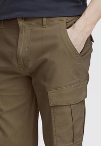 Beige cargo bukser med standard pasform, flere lommer, bæltestropper og et glat, let struktureret stof.