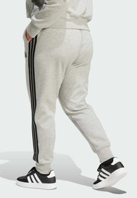 Housut vaaleanharmaata väriä, joissa mustat sivuviivat, joustava vyötärönauha ja taskut. Yhdistetty mustiin ja valkoisiin urheilukenkään.