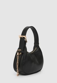 Schwarze Lederhandtasche mit geschwungener Form, goldfarbenen Beschlägen, Reißverschluss und einer Kettenverzierung am Träger.