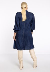 Denimkleid mit einem kragenf�örmigen Ausschnitt, voluminösen Ärmeln und einem Reißverschluss hinten. Abgeschlossen mit goldenen Knöpfen und einem leicht ausgestellten Saum.
