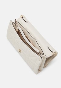 Quiltet cremet faux læder taske med guldfarvet hardware, der har et hovedrum og en lynlåslomme til organisering.