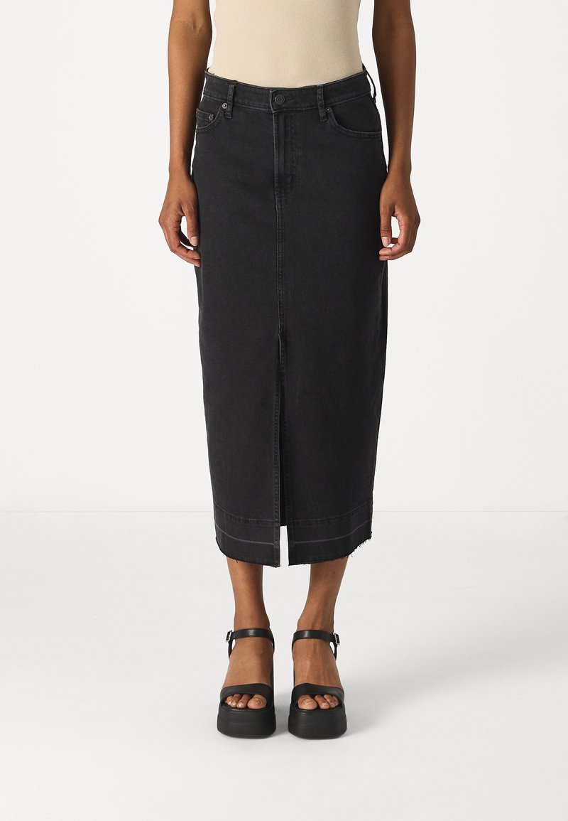 Fustă midi din denim negru, cu un design drept, slit frontal și tiv desfăcut. Finisată cu brâu și buzunare laterale. Asortată cu sandale cu platformă negre.