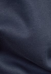 Tessuto di cotone blu navy con una texture liscia e una leggera elasticità, caratterizzato da un motivo a maglia uniforme e una lucentezza minima.