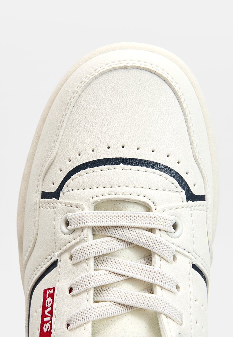 Zapatillas Levi's blancas con cordones beige, diseño curvado negro cerca de los dedos y una etiqueta del logo Levi's roja en el costado.
