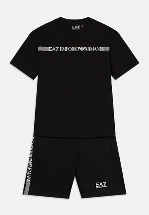 Černý set trička s krátkými rukávy a šortek s bílým nápisem "EA7 Emporio Armani" přes hruď a dolů na levé nohavici šortek.