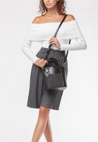 Borsa a mano in pelle nera con forma strutturata e superficie texturizzata. Caratterizzata da manici doppi e una tracolla removibile.