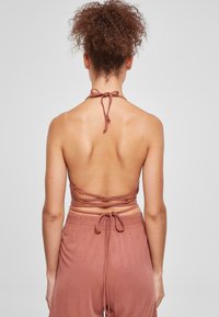 Brun halterneck topp med ryggsnøring og kryssdetaljer, laget av lett stoff, kombinert med matchende løse bukser.