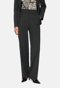Gray tailored trousers with a straight fit, featuring a fine texture. Paired with a patterned top and pointed black heels.