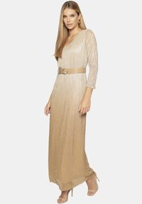 Długa, lśniąca złota sukienka z dekoltem w kształcie litery V, rękawami trzyczwartowymi i szerokim paskiem. Gładka tekstura z pionowymi fałdami i długością do podłogi.