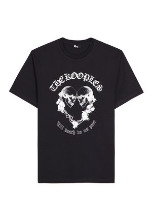 Musta T-paita, jossa valkoinen kuvio kahdesta vastakkain olevasta kallosta, jotka muodostavat sydämen, ympärillään kukka-aiheisia elementtejä ja teksti "THE KOOPLES" sekä "Till death do us part".