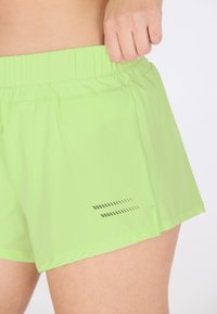 Ljust gröna träningsshorts med elastisk midja, rak skärning och subtil reflekterande detaljer på sidan. Mjukt, lätt tyg.