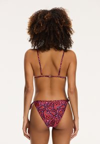 Bikinijski komplet z vijoličnim, rdečim in oranžnim paisley vzorcem, s tankimi trakovi in stranskimi vezalkami, izdelan iz gladkega in elastičnega materiala.