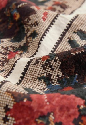 Textile featuring intricate floral and geometric patterns in warm reds, blues, and browns, with a soft textured surface and checkered accents.