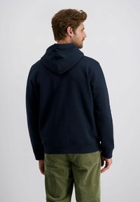 Marineblaues Hoodie mit Kordelzugkapuze, gerippten Bündchen und Saum. Geeignet für legere Outfits, kombiniert mit grünen Cordhosen.