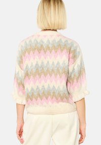 Stickad tröja med ett zigzag-mönster i pastellrosa, blått och beige på en krämfärgad bakgrund; lös passform med 3/4 ärmar.