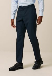 Formelle marineblaue Hose mit glatter Textur, slim fit und Bügelfalte, kombiniert mit schwarzen Lederschuhen.