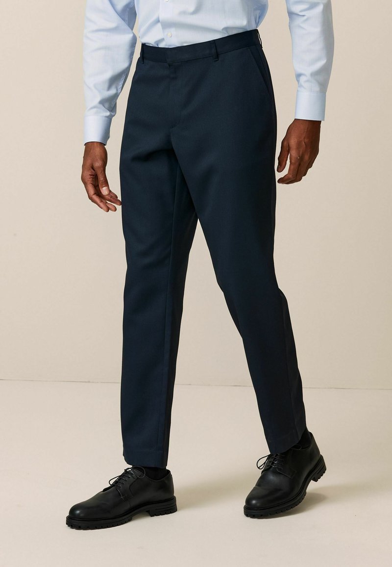 Formelle marineblaue Hose mit glatter Textur, slim fit und Bügelfalte, kombiniert mit schwarzen Lederschuhen.