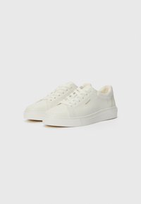 Sneakers bianchi in pelle con punta tonda, lacci frontali, pannelli texturizzati e un logo discreto sul lato. Suola in gomma spessa.