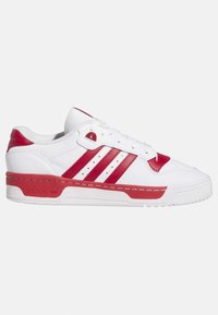 Zapatilla deportiva blanca con detalles en rojo, que presenta tres rayas rojas, materiales de cuero texturizado y goma, y un diseño de cuello acolchado.
